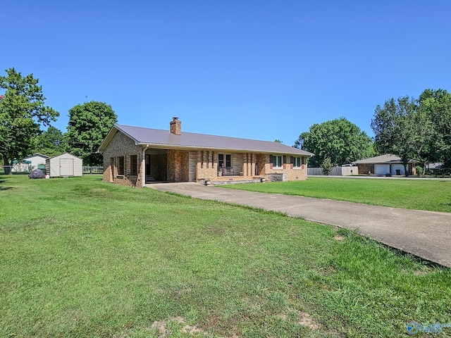 single story home featuring a front yard, an outbuilding, aphalt driveway, brick siding, and metal roof