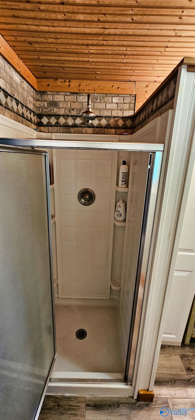 bathroom featuring a shower with shower door, hardwood / wood-style floors, and wooden ceiling