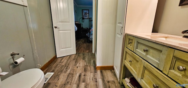 bathroom featuring crown molding, wood-type flooring, vanity, and toilet