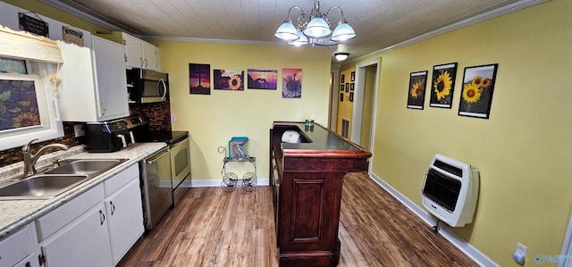 kitchen featuring pendant lighting, ornamental molding, heating unit, white cabinetry, and stainless steel appliances