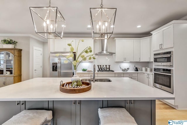 kitchen featuring stainless steel appliances, white cabinetry, sink, and wall chimney exhaust hood