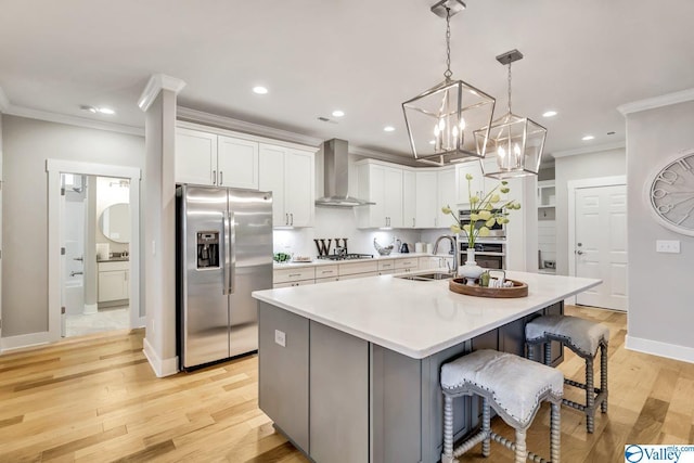 kitchen with wall chimney exhaust hood, white cabinetry, stainless steel appliances, and a center island with sink