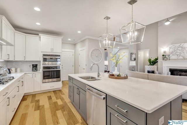 kitchen with white cabinetry, appliances with stainless steel finishes, a center island with sink, and gray cabinetry