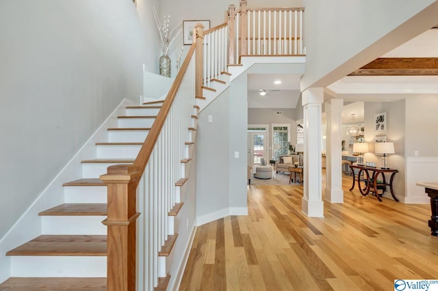 stairs with hardwood / wood-style floors, a high ceiling, and ornate columns