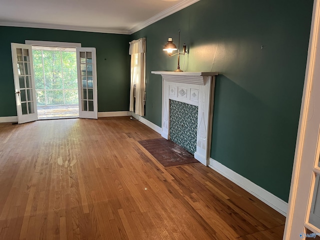 unfurnished living room with a fireplace with flush hearth, ornamental molding, wood finished floors, and baseboards