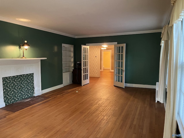 unfurnished living room with french doors, a tile fireplace, wood finished floors, and crown molding