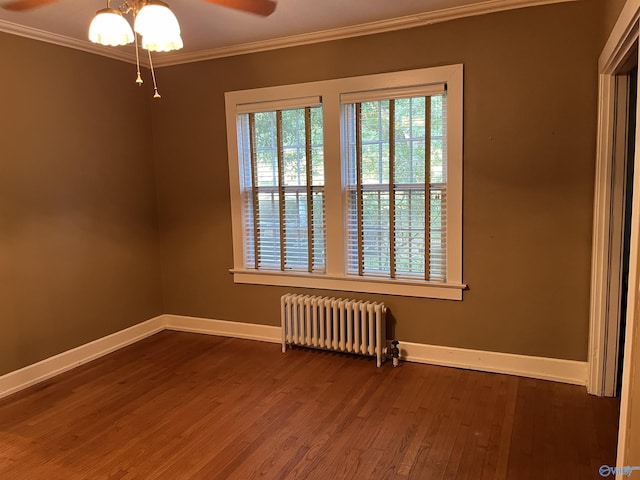empty room featuring dark wood-style floors, radiator heating unit, baseboards, and crown molding