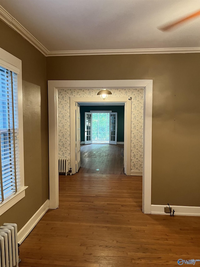 corridor with wallpapered walls, radiator heating unit, wood finished floors, and crown molding