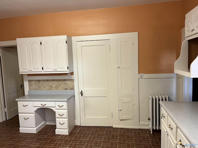 unfurnished office with radiator heating unit and brick floor