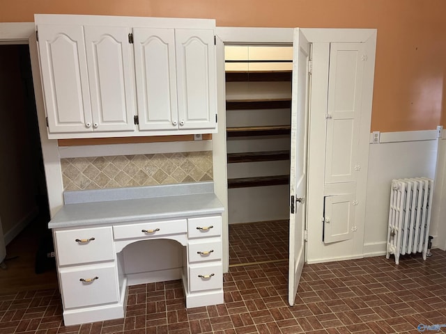 unfurnished office with brick floor and radiator