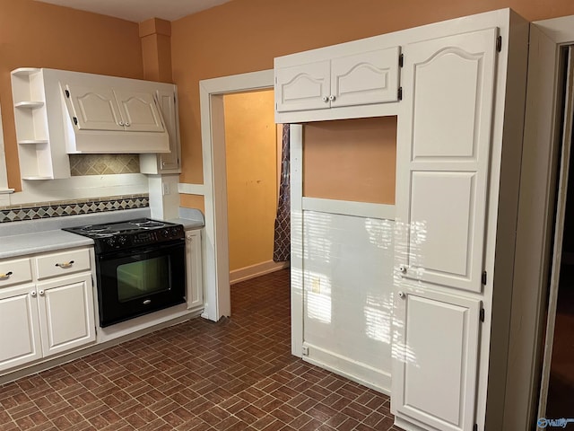 kitchen featuring electric range, white cabinets, light countertops, open shelves, and tasteful backsplash