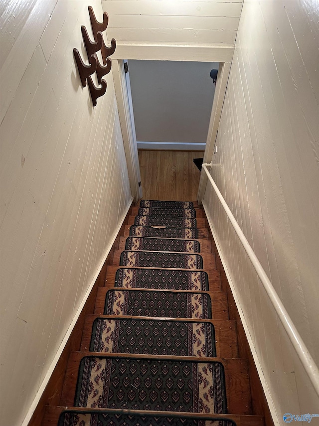 stairway featuring wood finished floors and wooden walls