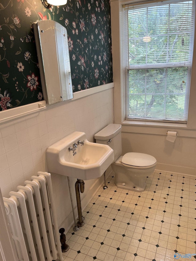 bathroom with plenty of natural light, wallpapered walls, wainscoting, and radiator