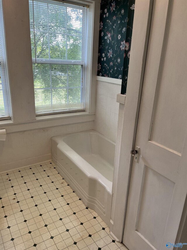 bathroom featuring a wainscoted wall, tile patterned floors, a garden tub, and wallpapered walls