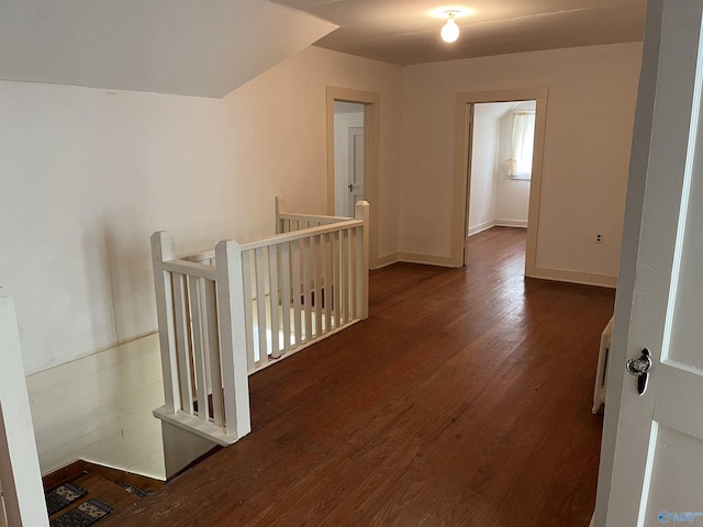 hall with baseboards, hardwood / wood-style floors, and an upstairs landing