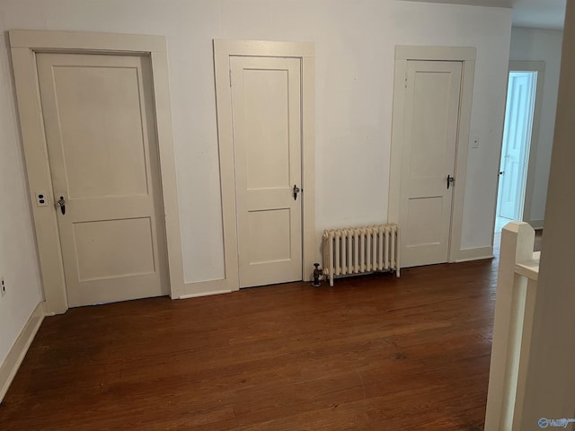 interior space with dark wood-type flooring, radiator, and baseboards