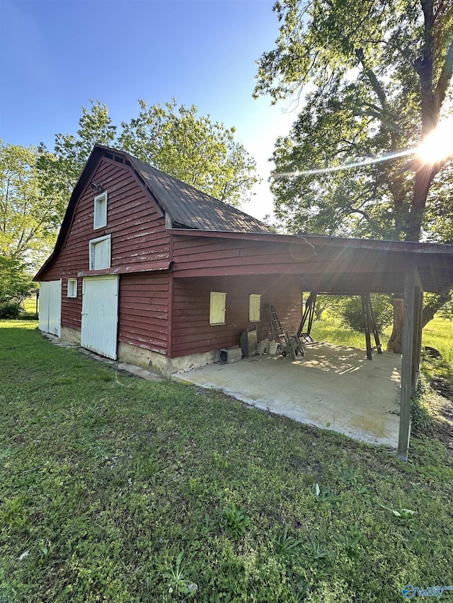 view of side of home with an attached carport, a patio area, and a lawn