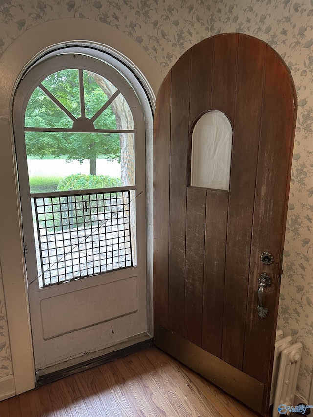 doorway featuring radiator, wood-type flooring, and wallpapered walls