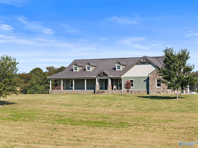 view of front of house with metal roof, a front yard, covered porch, and stone siding