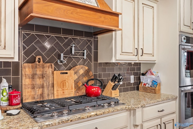 kitchen featuring custom range hood, light stone countertops, decorative backsplash, and stainless steel appliances