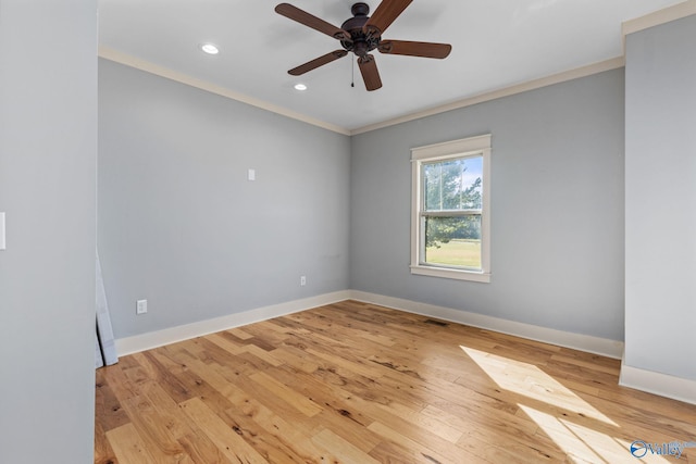 empty room with crown molding, a ceiling fan, light wood finished floors, baseboards, and visible vents