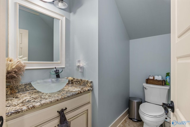 bathroom featuring baseboards, lofted ceiling, toilet, and vanity