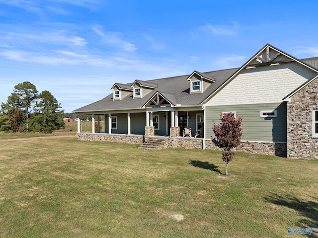 view of front of home with a front yard, stone siding, a porch, and metal roof