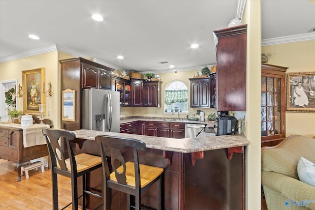 kitchen with crown molding, a peninsula, visible vents, appliances with stainless steel finishes, and light countertops