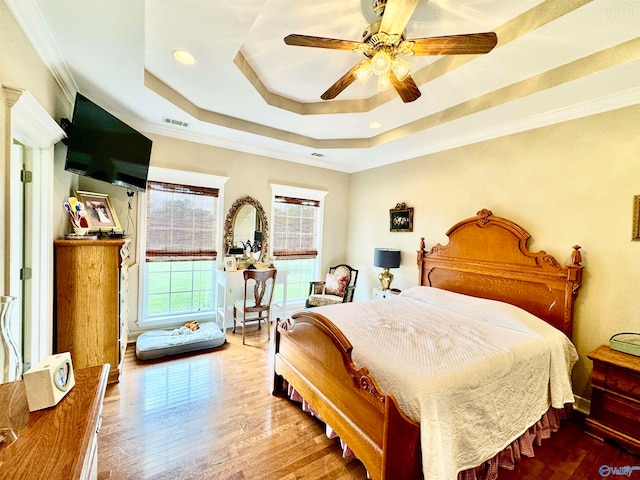 bedroom featuring a tray ceiling, ceiling fan, hardwood / wood-style flooring, and crown molding