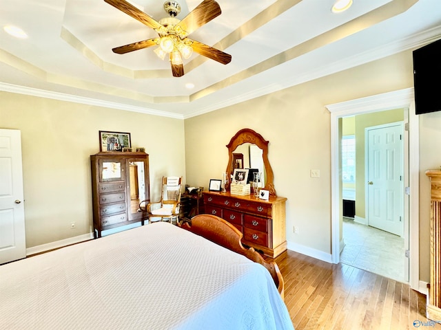 bedroom featuring crown molding, a raised ceiling, ceiling fan, and light hardwood / wood-style floors