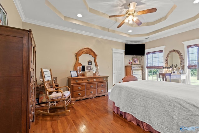 bedroom featuring a raised ceiling, wood-type flooring, ornamental molding, and recessed lighting