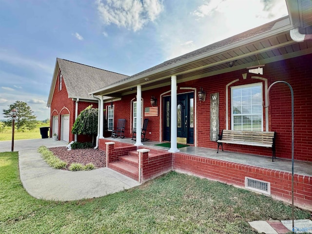 exterior space featuring a front yard, covered porch, and a garage