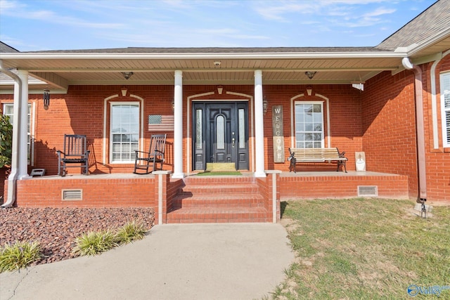 entrance to property with covered porch and brick siding