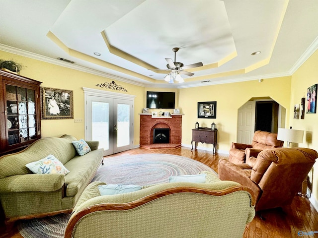 living room with crown molding, ceiling fan, hardwood / wood-style flooring, and a tray ceiling