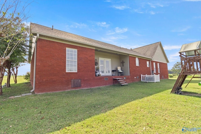 rear view of house featuring brick siding, french doors, and a lawn