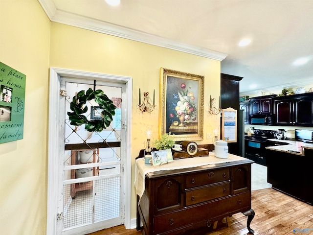 kitchen with light wood-type flooring, black appliances, and crown molding