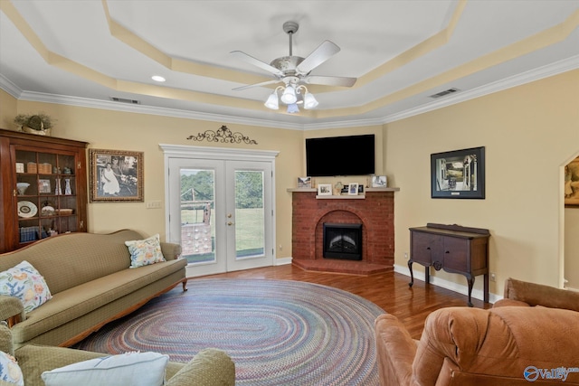 living room with visible vents, a tray ceiling, and ornamental molding