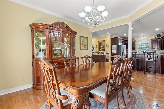dining room featuring baseboards, ornamental molding, decorative columns, a chandelier, and light wood-style flooring