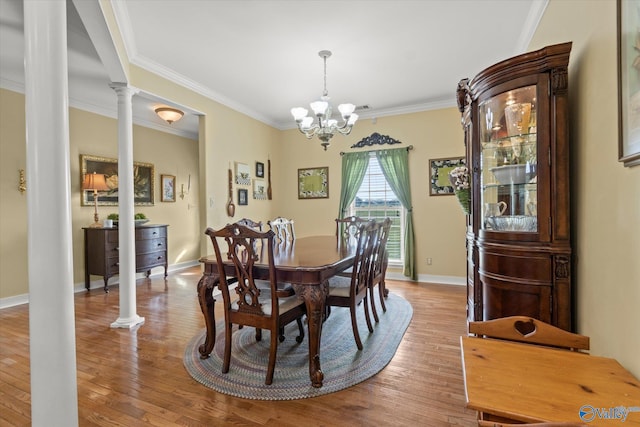dining space with crown molding, decorative columns, an inviting chandelier, and wood finished floors