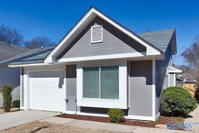 view of front of house with an attached garage, concrete driveway, and roof with shingles