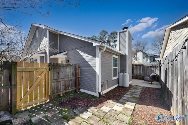 back of house with a patio area, a gate, a chimney, and fence