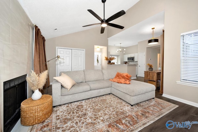 living area with dark wood-style floors, visible vents, vaulted ceiling, baseboards, and ceiling fan with notable chandelier