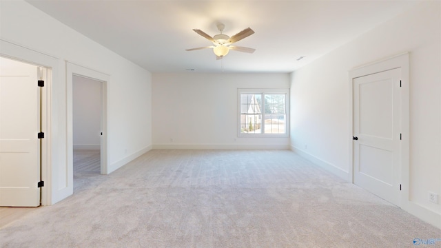 unfurnished room with ceiling fan, light colored carpet, and baseboards