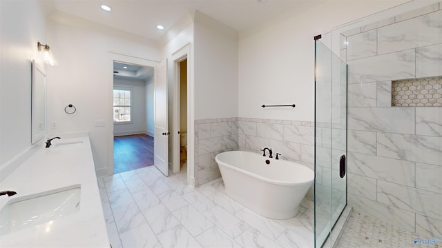 full bathroom featuring a soaking tub, a shower stall, a sink, and marble finish floor
