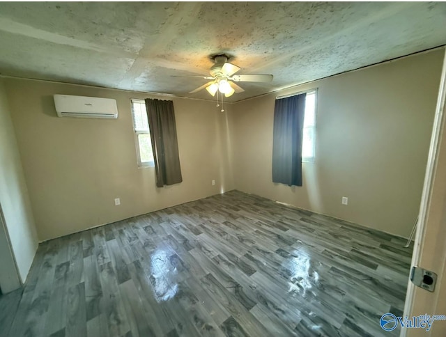 spare room featuring a wall mounted air conditioner, light hardwood / wood-style flooring, and ceiling fan