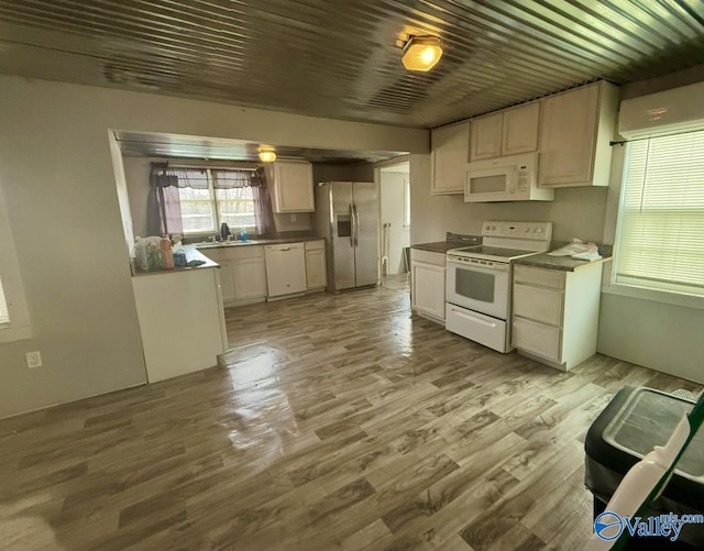 kitchen featuring sink, white cabinetry, a wall mounted air conditioner, light wood-type flooring, and white appliances