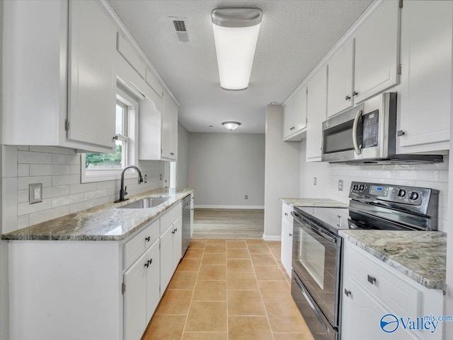 323 Earnhardt Dr, New Market, AL 35761 - kitchen featuring appliances with stainless steel finishes, a sink, baseboards, white cabinetry, and a textured ceiling