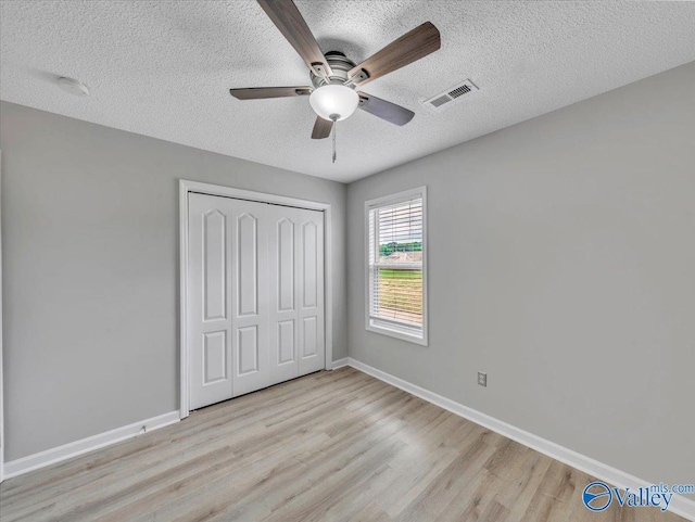 323 Earnhardt Dr, New Market, AL 35761 - unfurnished bedroom featuring a textured ceiling, light wood finished floors, a closet, baseboards, and a ceiling fan