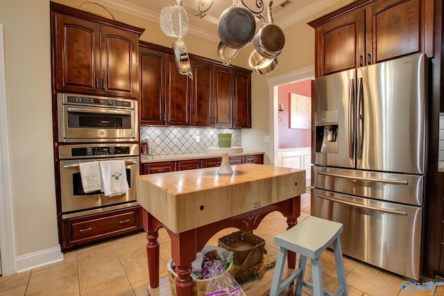 kitchen featuring ornamental molding, backsplash, appliances with stainless steel finishes, butcher block counters, and light tile patterned floors
