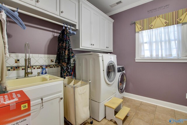 washroom featuring light tile patterned floors, visible vents, washing machine and clothes dryer, cabinet space, and ornamental molding